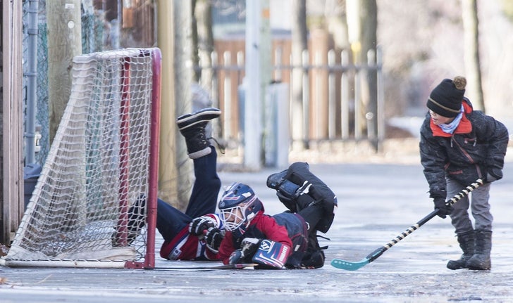 Des enfants jouent au hockey dans une rue de Montréal.